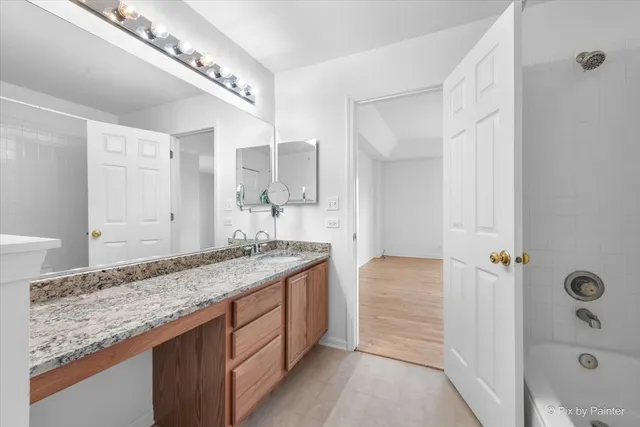a bathroom with a granite countertop sink a mirror and shower