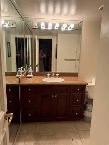 a bathroom with a granite countertop sink toilet and mirror