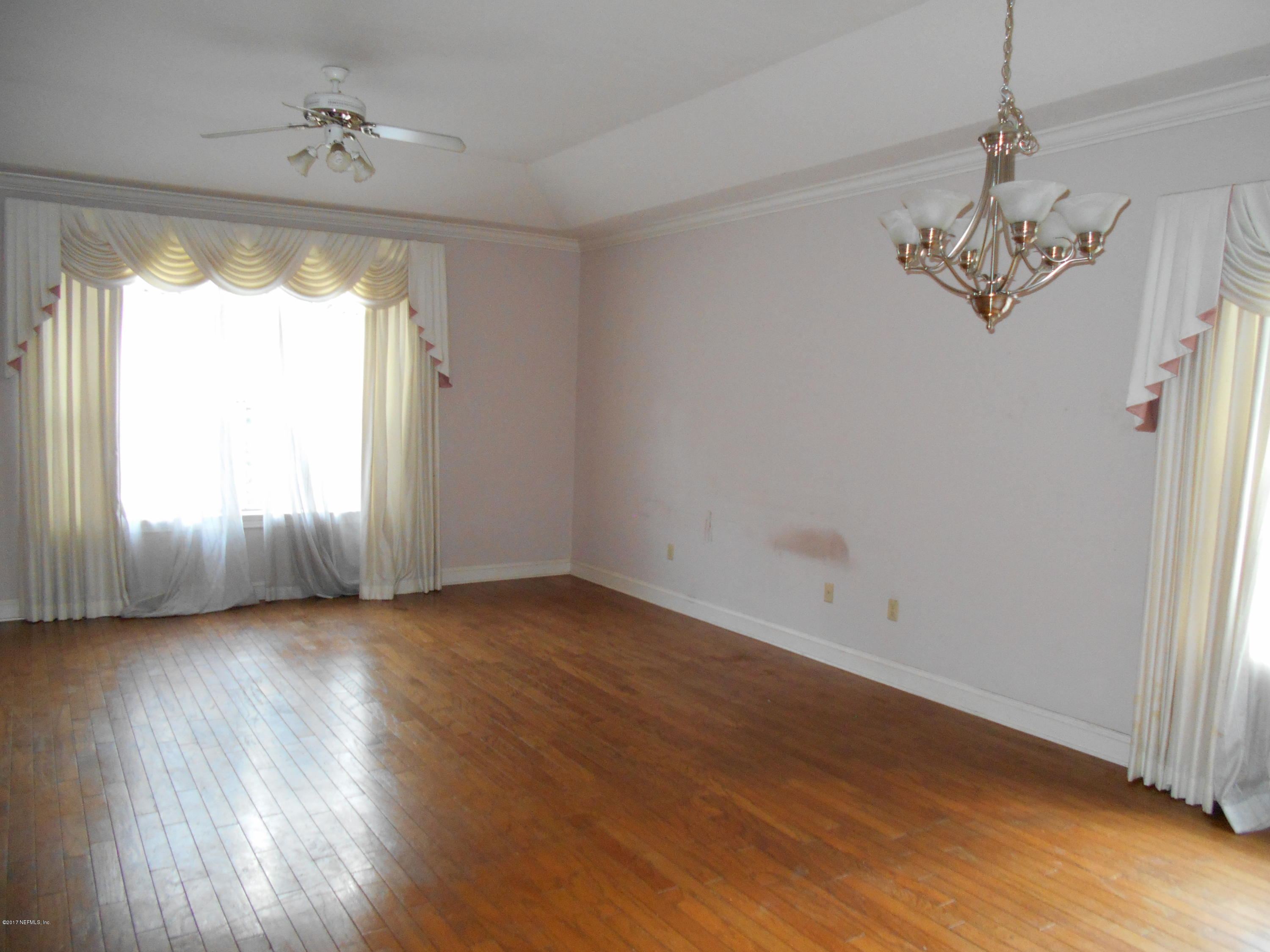3006 Holly Road Orange Park, FL 32065 - Photo 9 of 19 an empty room with wooden floor chandelier and windows