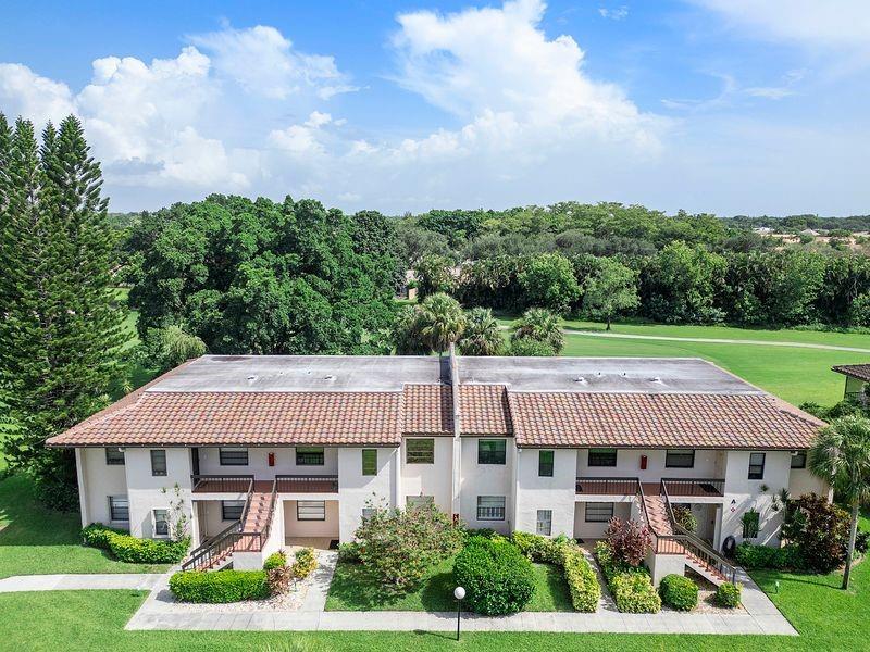 21452 Juego Circle, Unit 31A Boca Raton, FL 33433 - Photo 3 of 38 a view of a big house with a big yard and large trees