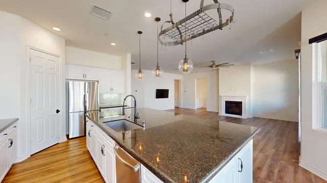 a kitchen with kitchen island granite countertop a sink a counter space appliances and cabinets