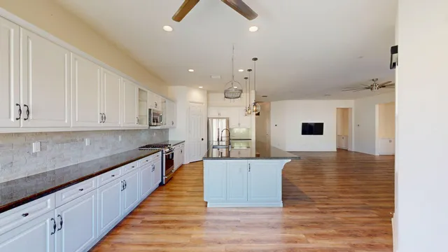 a large kitchen with kitchen island a sink dishwasher a stove and a refrigerator with wooden floor