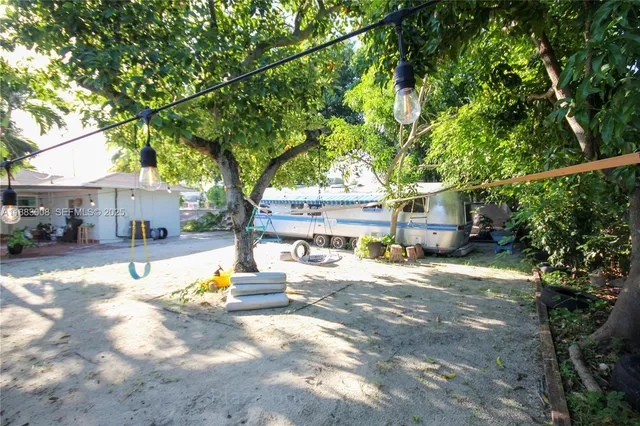 a view of a house with large tree and wooden fence