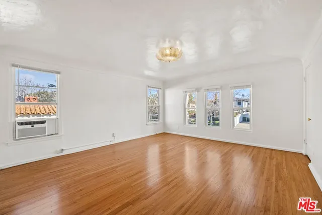 a view of an empty room with window and wooden floor