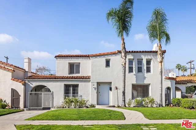 a front view of a house with a garden and palm trees