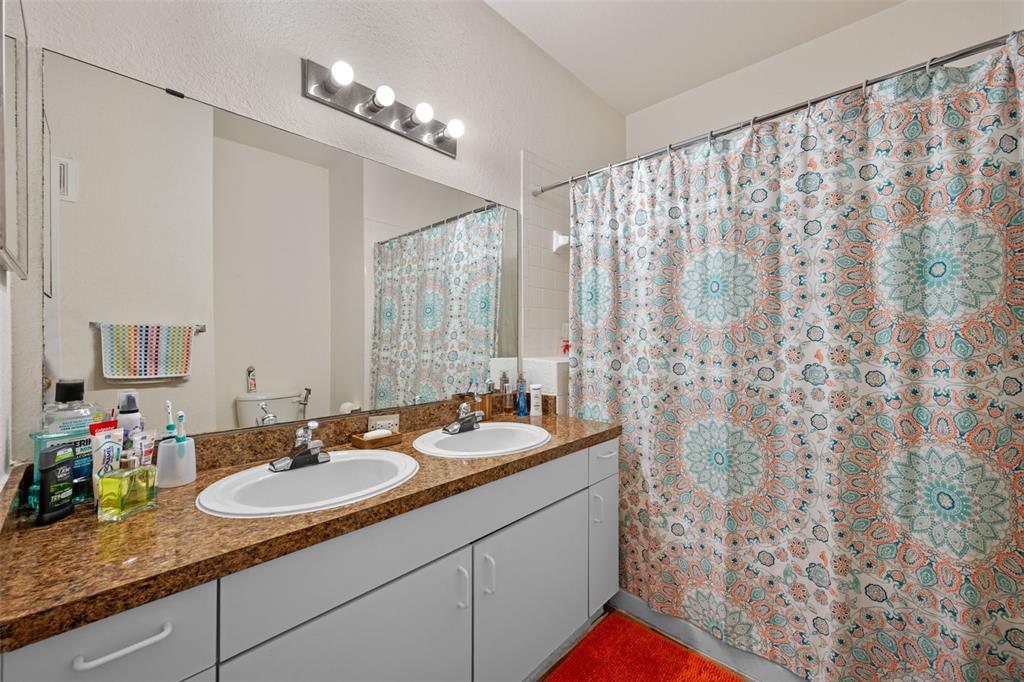 3701 Conroy Road, Unit 1812 Orlando, FL 32839 - Photo 18 of 37 a bathroom with a granite countertop sink a mirror and shower curtain
