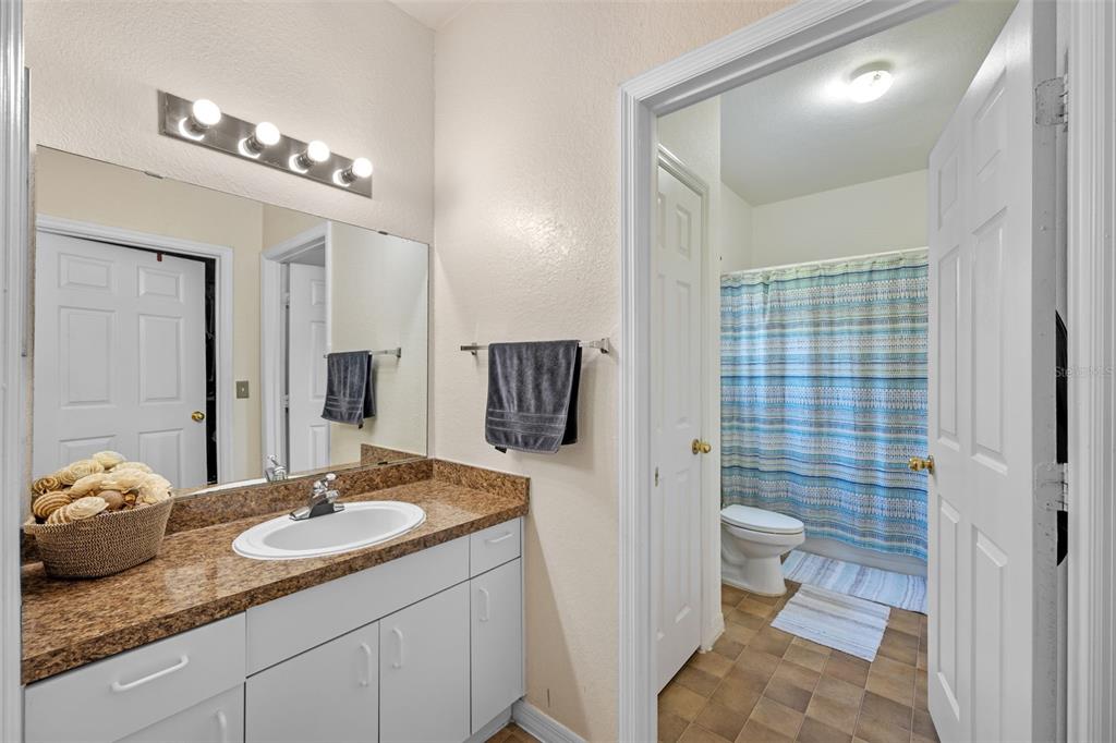 3701 Conroy Road, Unit 1812 Orlando, FL 32839 - Photo 23 of 37 a bathroom with a granite countertop sink a toilet a shower and a mirror