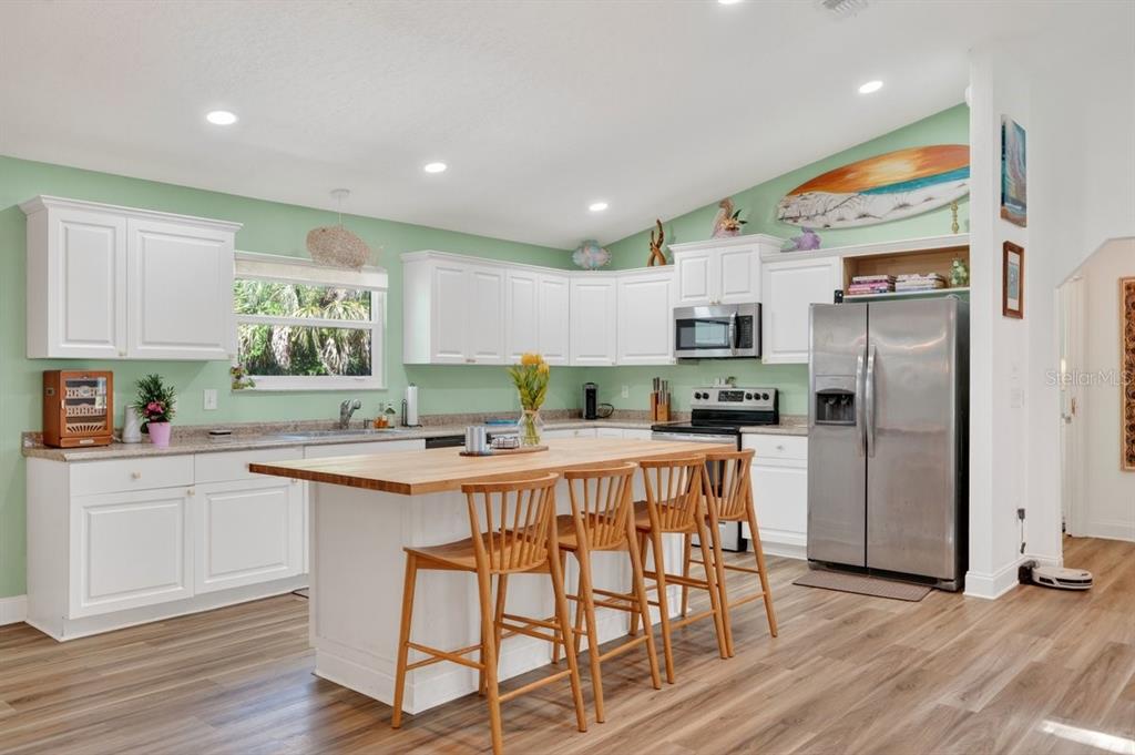 2012 Mango Tree Drive Edgewater, FL 32141 - Photo 17 of 36 a kitchen with stainless steel appliances granite countertop a refrigerator a stove top oven a sink dishwasher and white cabinets with wooden floor