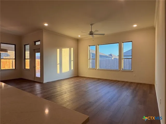 a view of an empty room with window and wooden floor