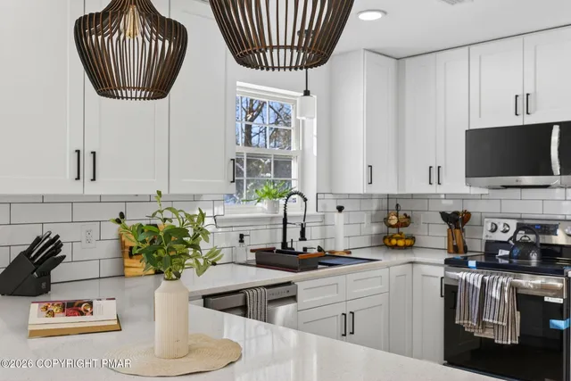 a kitchen with stainless steel appliances a sink a counter top space cabinets a stove and a window