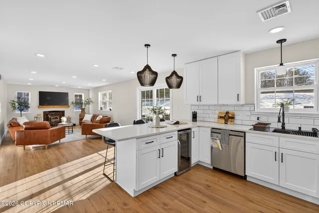 a kitchen with stainless steel appliances granite countertop a sink a stove and a wooden floors