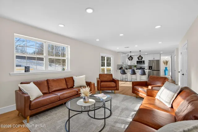 a living room with furniture wooden floor and kitchen view