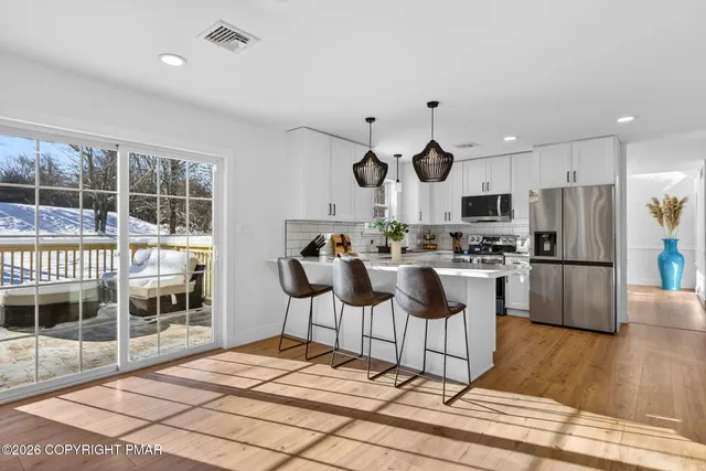 a kitchen with stainless steel appliances kitchen island granite countertop a refrigerator and a wooden cabinets