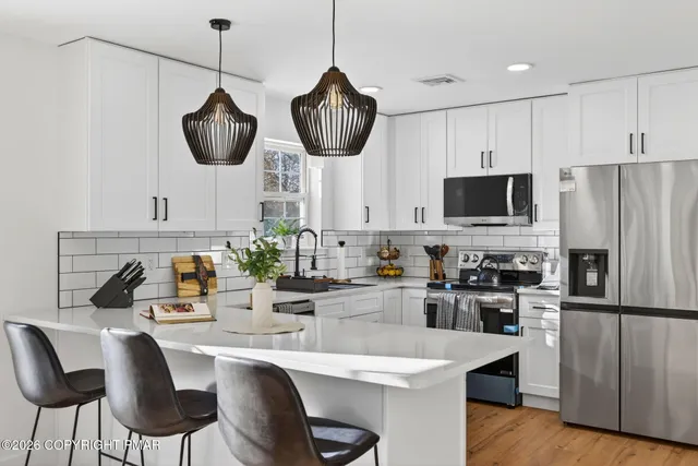 a kitchen with stainless steel appliances granite countertop a sink a stove a refrigerator and chairs