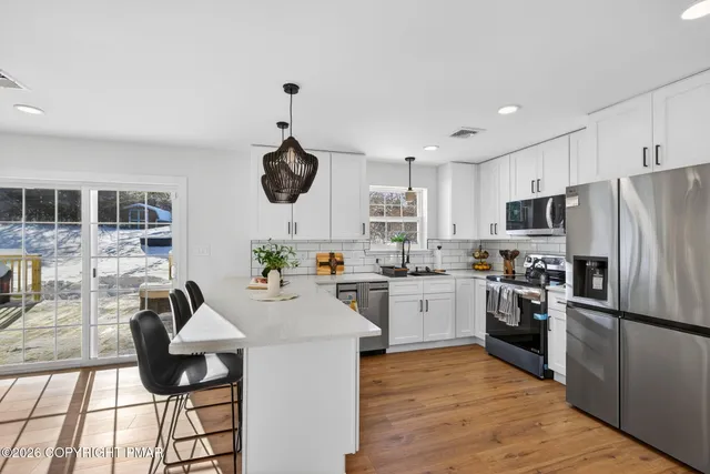 a kitchen with a refrigerator a stove top oven a sink dishwasher and white cabinets with wooden floor