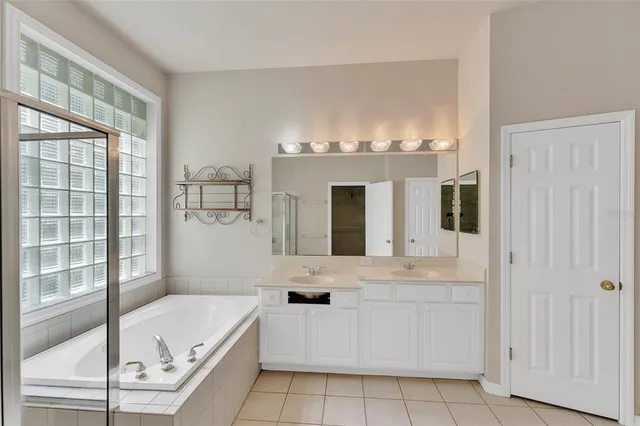 a bathroom with a granite countertop tub a sink and a large mirror