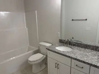 a bathroom with a granite countertop sink a toilet and shower