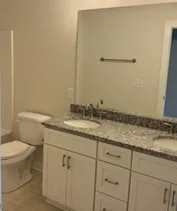 a bathroom with a granite countertop sink and a toilet