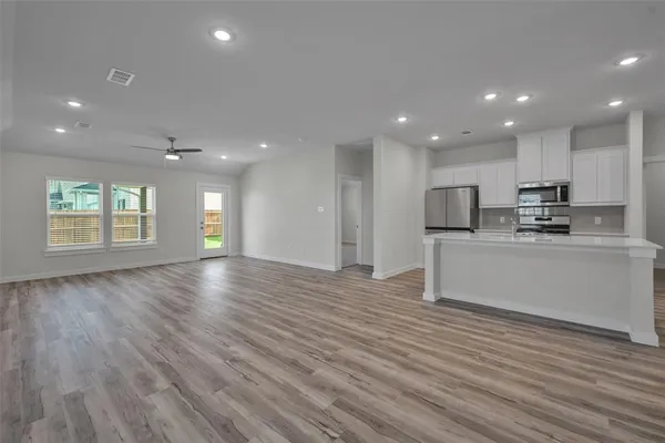 a view of kitchen with kitchen island microwave and wooden floor