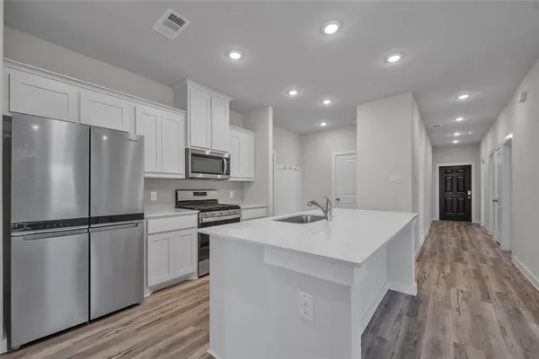 a kitchen with kitchen island a sink stainless steel appliances and cabinets