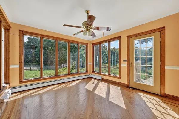 a view of an empty room with a window and wooden floor