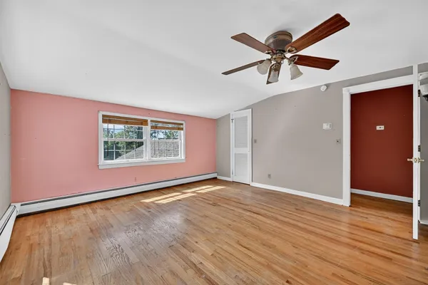 a view of an empty room with a window and wooden floor