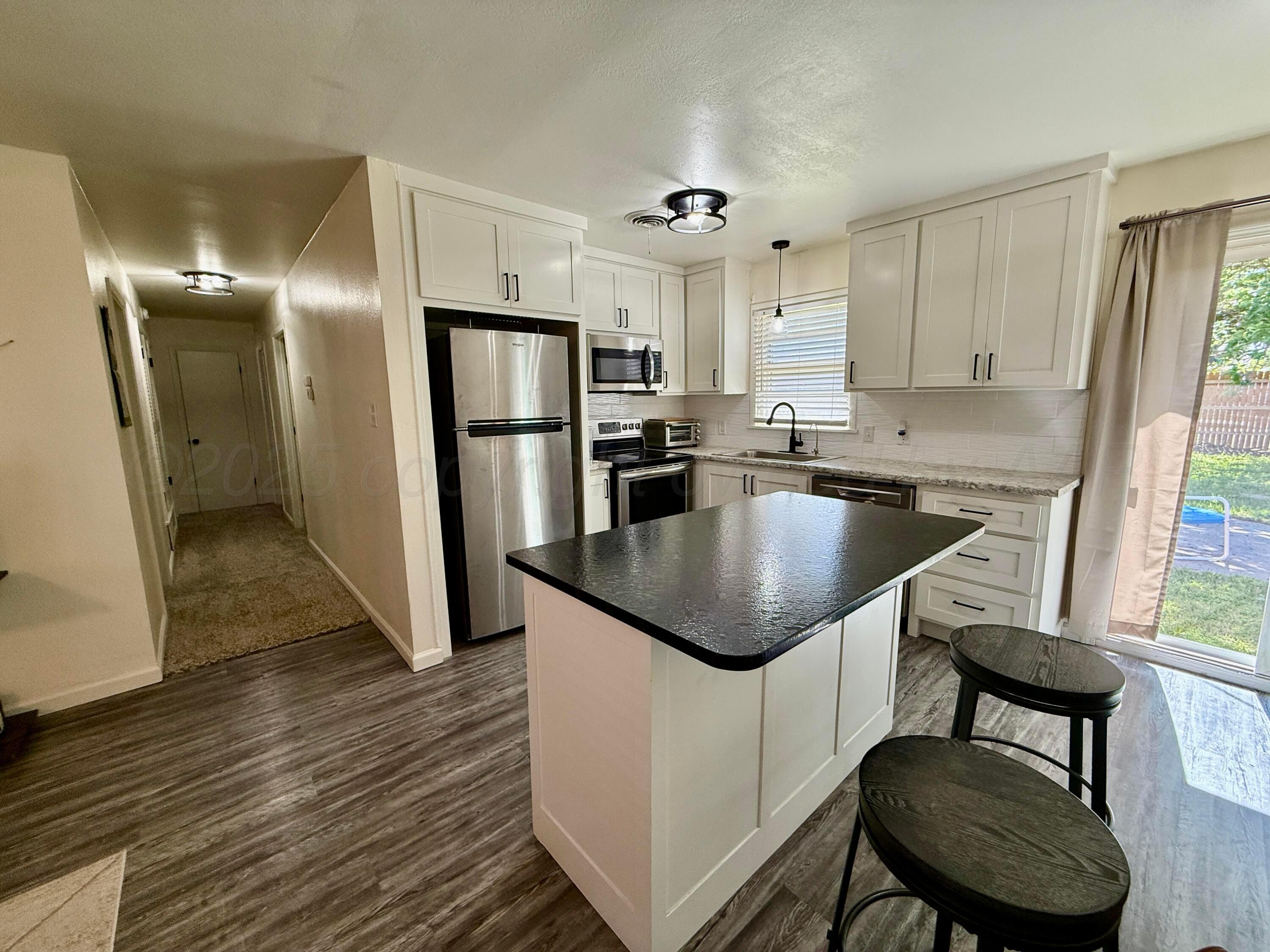 4600 South Bryan Street Amarillo, TX 79110 - Photo 3 of 13 a kitchen with kitchen island a counter top space cabinets stainless steel appliances and windows