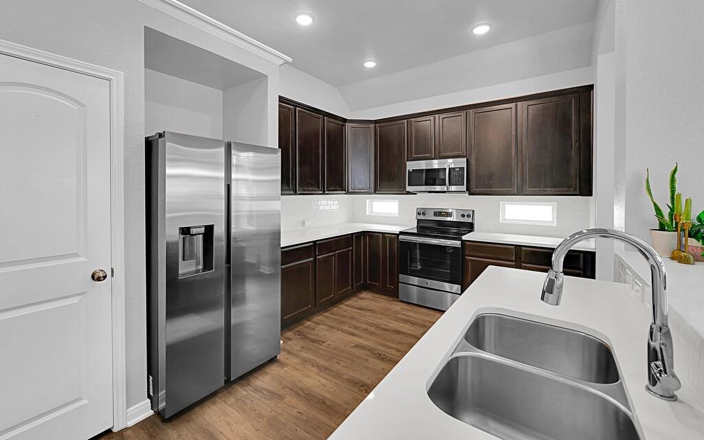 2720 Beutel Road Lorena, TX 76655 - Photo 11 of 37 Kitchen featuring stainless steel appliances, dark brown cabinetry, dark wood-style flooring, a textured wall, and decorative backsplash