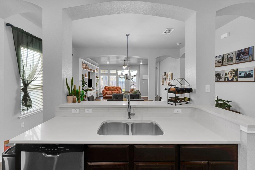 2720 Beutel Road Lorena, TX 76655 - Photo 36 of 37 Kitchen with a textured wall, open floor plan, stainless steel dishwasher, dark brown cabinets, and arched walkways