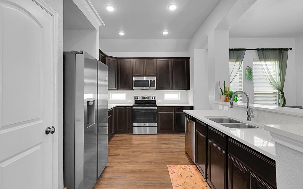 2720 Beutel Road Lorena, TX 76655 - Photo 10 of 37 Kitchen featuring dark brown cabinets, appliances with stainless steel finishes, light wood-type flooring, light stone counters, and recessed lighting
