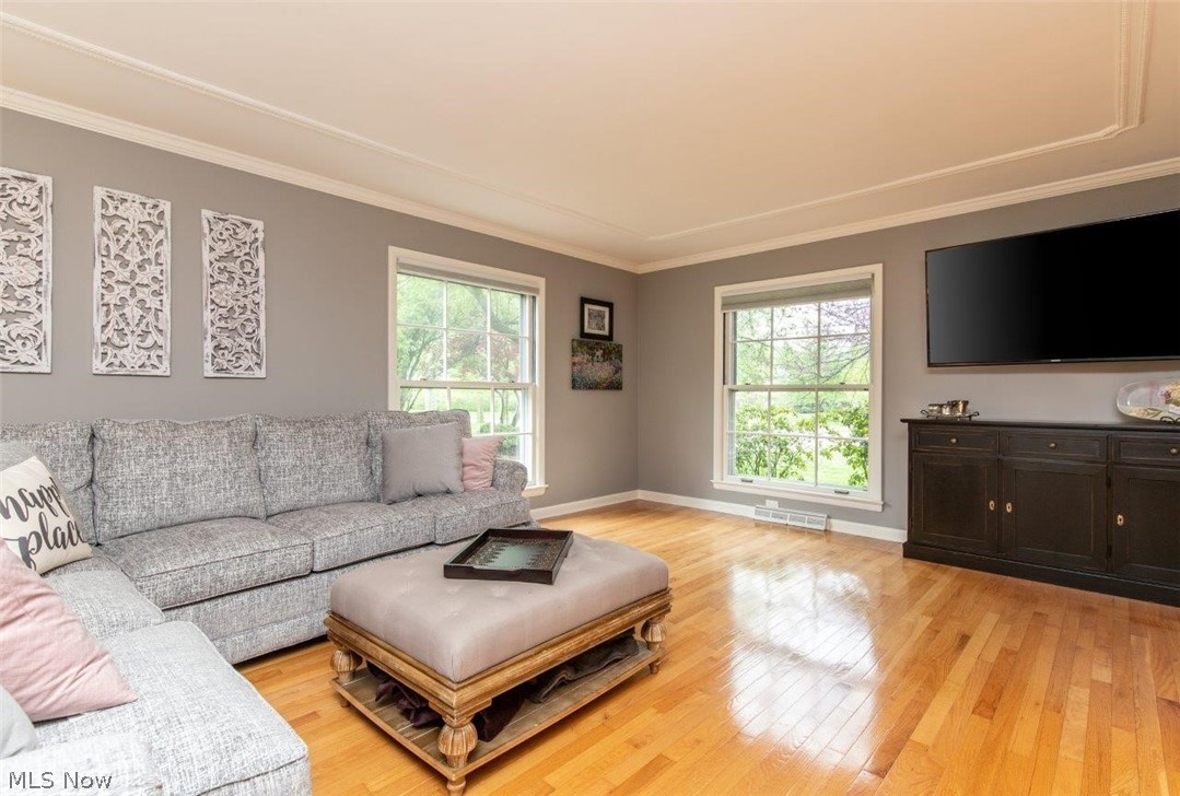 Spacious Living Room with Hardwood Floors, Two Sided Fireplace and Custom Moldings
