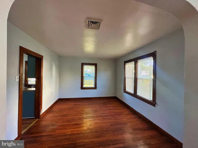 a view of an empty room with glass door and wooden floor