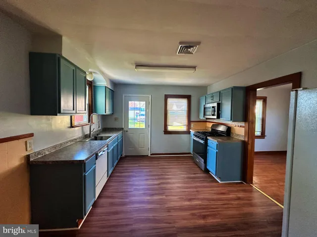 a large kitchen with a center island wooden floor and stainless steel appliances