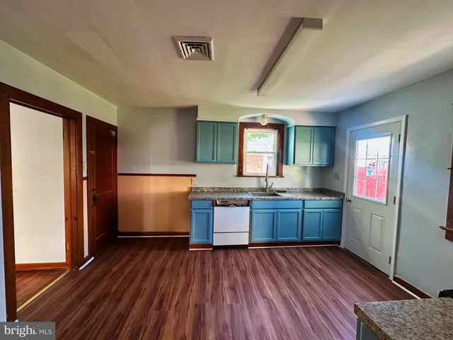 a kitchen with a refrigerator and wooden floor