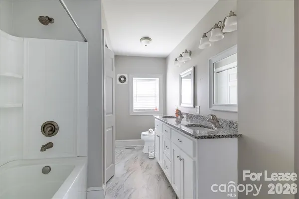 a spacious bathroom with a granite countertop sink a mirror and a bathtub