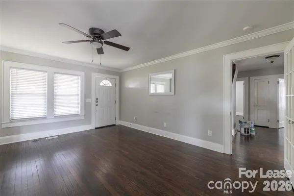 a view of an empty room with wooden floor and a window