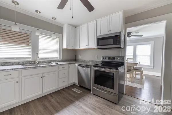 a kitchen with granite countertop a stove a sink and a microwave