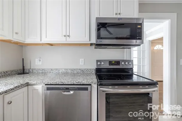 a kitchen with stainless steel appliances granite countertop white cabinets granite counter tops and a wooden floors
