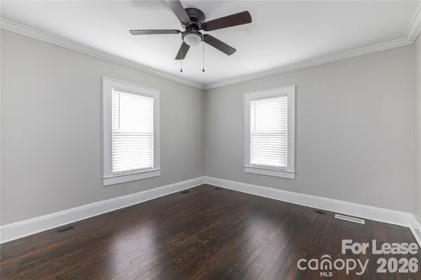 an empty room with wooden floor fan and windows