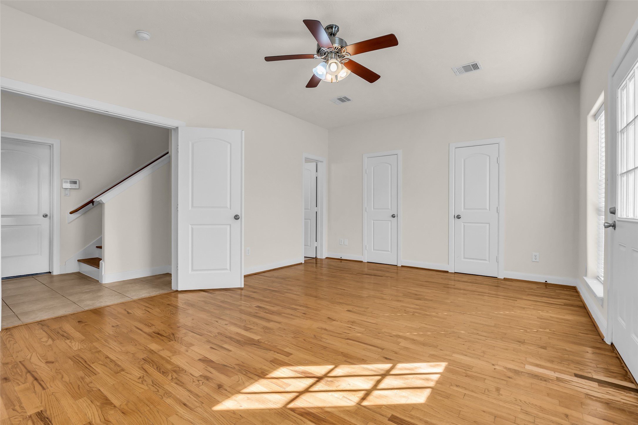1803 Stacy Crest Houston, TX 77008 - Photo 3 of 28 The first-floor bedroom featuring wooden floors and large windows that bring in natural light. The space includes a private bathroom and a walk-in closet discreetly hidden behind the closed doors shown in the photo.