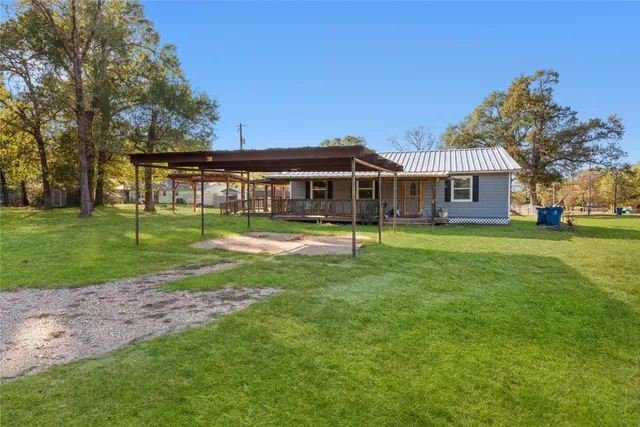 a view of a house next to a big yard and large trees