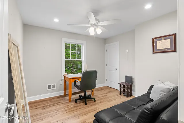 a living room with stainless steel appliances furniture a dining table wooden floor and kitchen view
