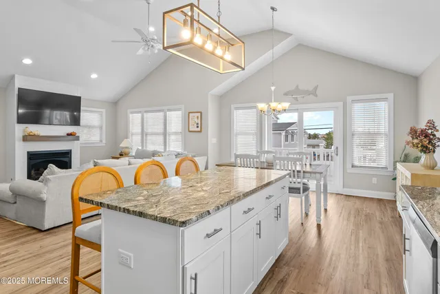 a kitchen with stainless steel appliances granite countertop a stove top oven a sink dishwasher a dining table and chairs with wooden floor