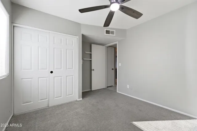 an empty room with a ceiling fan and a window