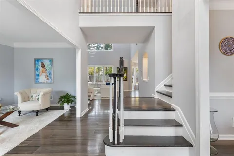 a kitchen with a sink dishwasher and white cabinets with wooden floor