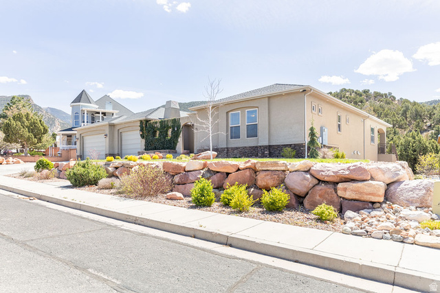 View of front of home featuring stucco siding, a garage, and stone siding