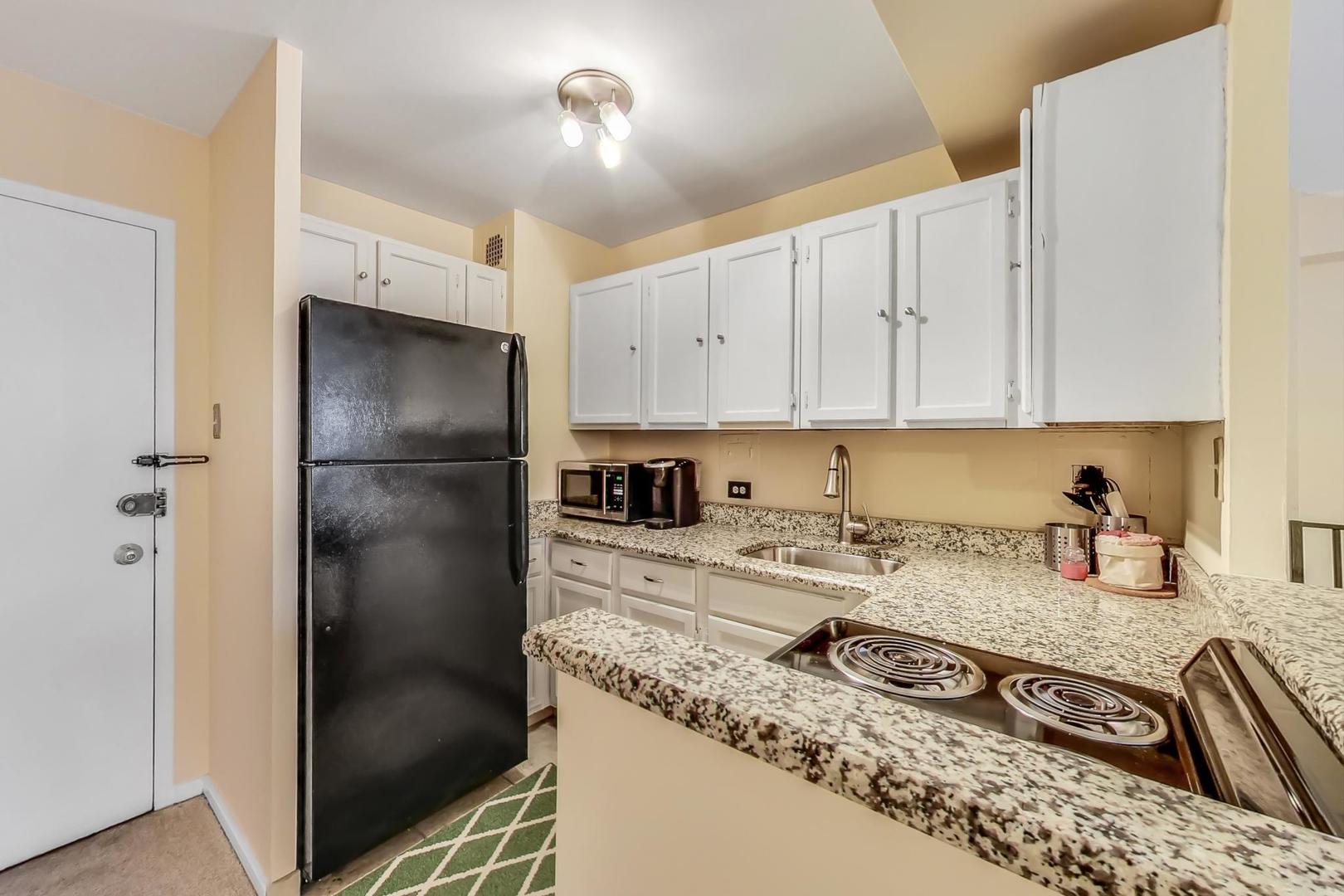 2909 North Sheridan Road, Unit 411 Chicago, IL 60657 - Photo 6 of 15 a kitchen with kitchen island granite countertop a refrigerator a stove and a sink