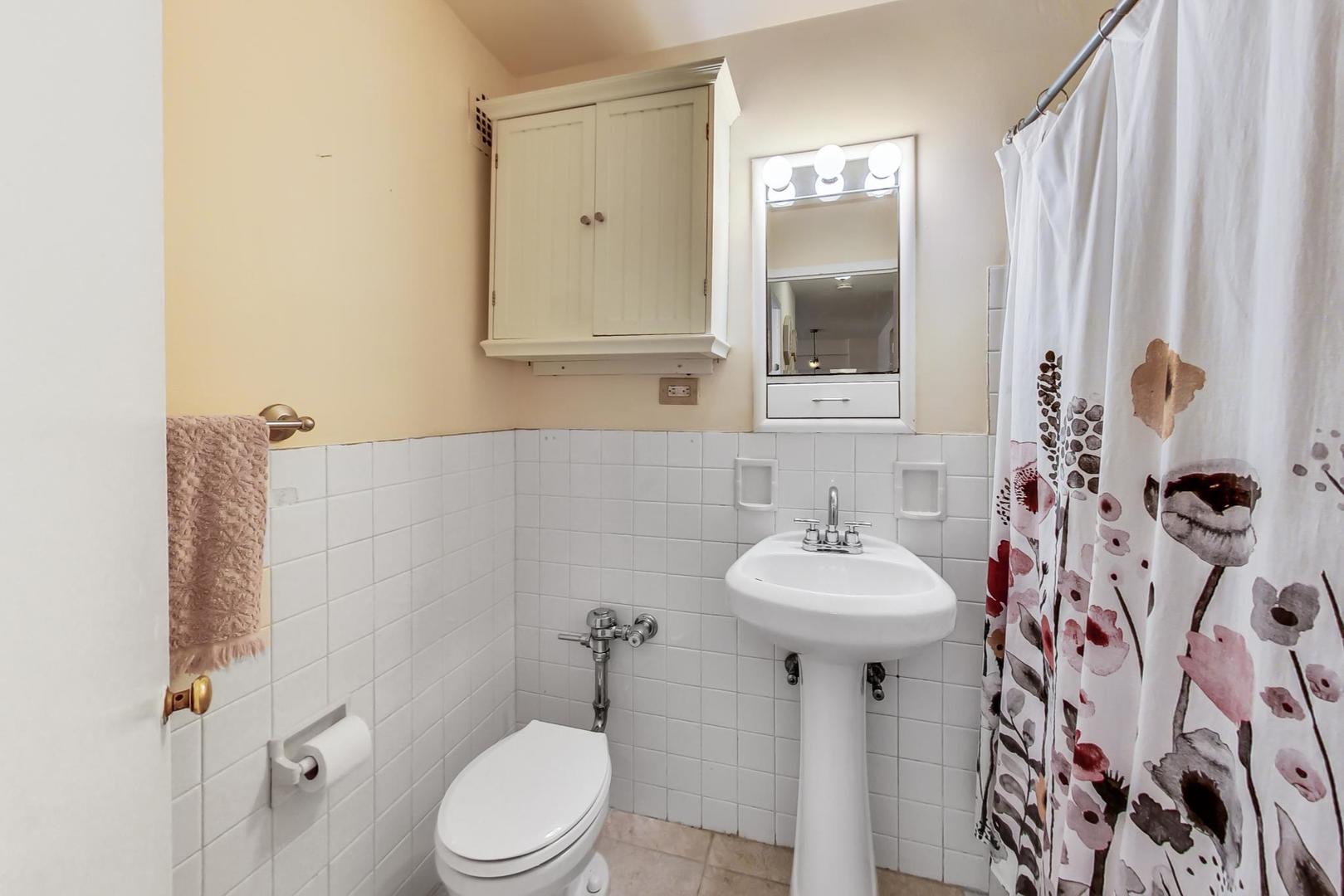2909 North Sheridan Road, Unit 411 Chicago, IL 60657 - Photo 8 of 15 a bathroom with a sink mirror and toilet