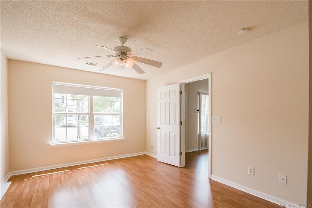 11228 Grass Field Road Charlotte, NC 28213 - Photo 16 of 26 an empty room with wooden floor chandelier fan and windows