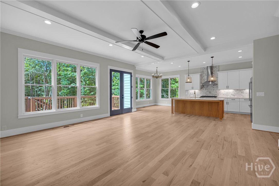 2476 St Martin Way Monroe, GA 30656 - Photo 12 of 75 Expansive open-concept room featuring light wood-finish flooring, a tray ceiling with recessed lighting and a ceiling fan, and large windows
